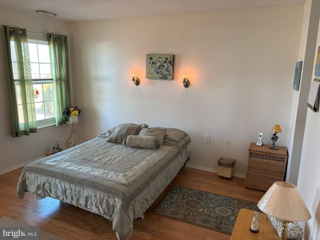 bedroom featuring baseboards, visible vents, and wood finished floors