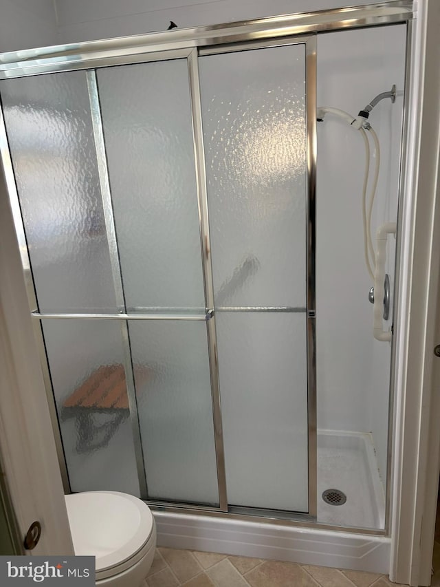 full bathroom with toilet, a stall shower, and tile patterned flooring