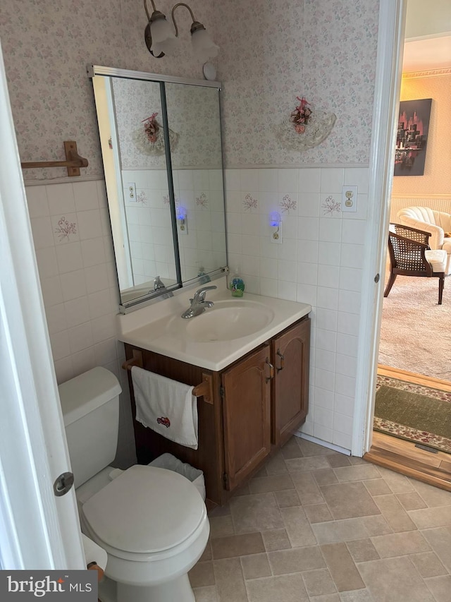 bathroom with a wainscoted wall, vanity, toilet, and wallpapered walls