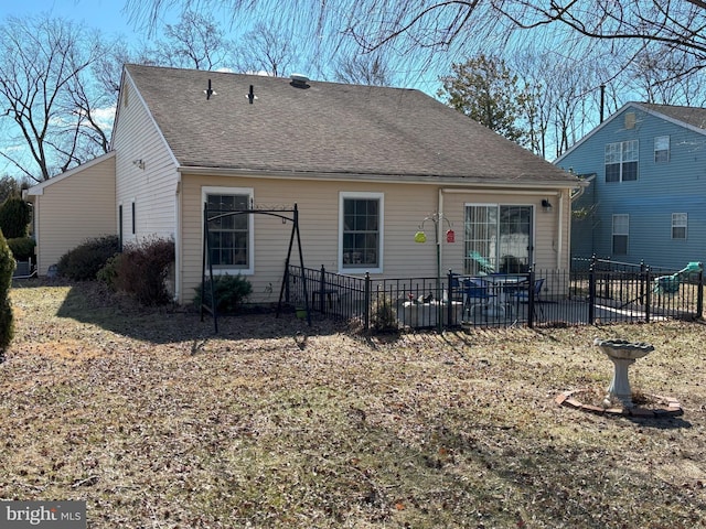 rear view of property with a shingled roof and fence