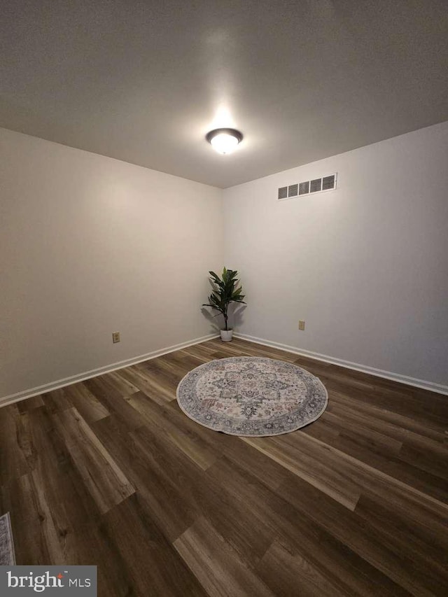 unfurnished room featuring baseboards, visible vents, and dark wood-type flooring