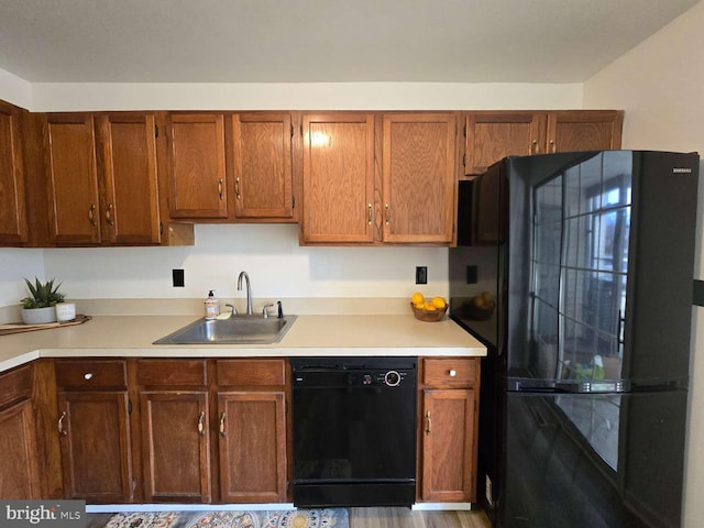 kitchen featuring brown cabinetry, light countertops, a sink, and black appliances