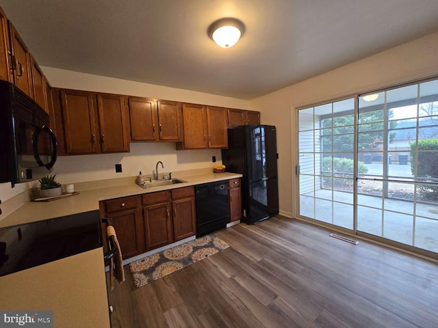 kitchen with light countertops, visible vents, a sink, wood finished floors, and black appliances