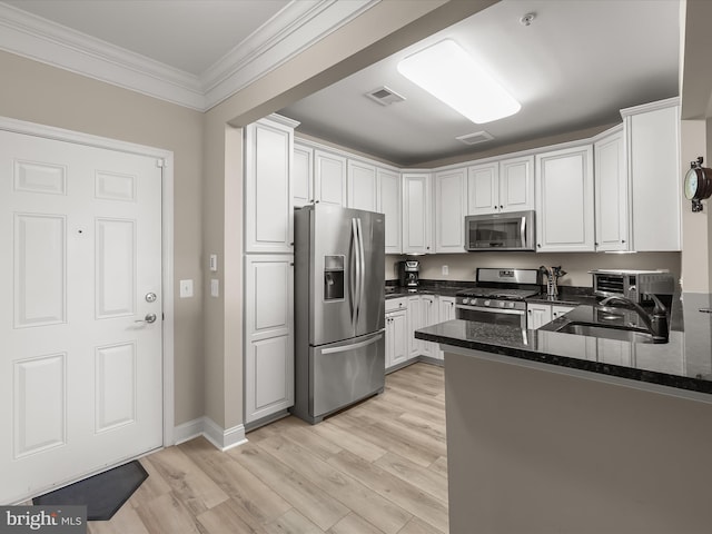 kitchen with light wood-style flooring, a sink, visible vents, ornamental molding, and appliances with stainless steel finishes