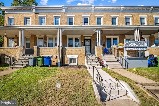 townhome / multi-family property with brick siding and a front yard