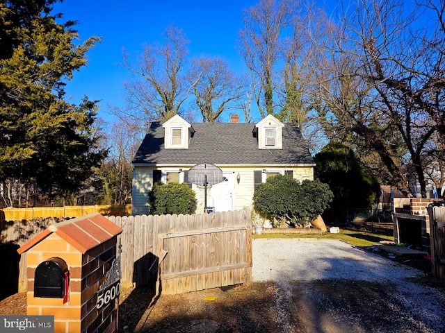 cape cod house with roof with shingles, fence, and driveway