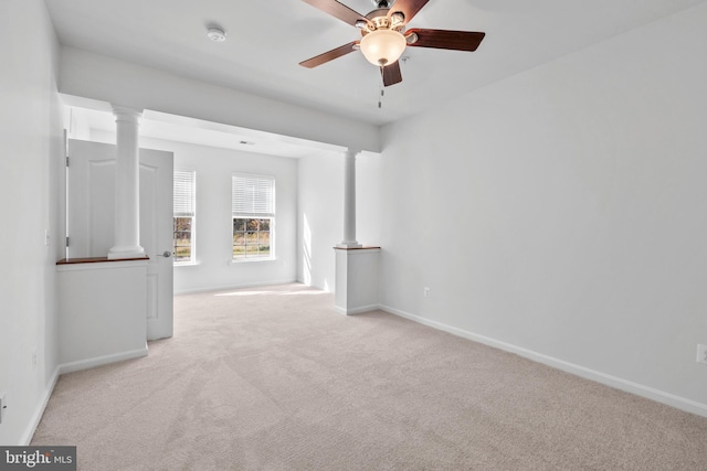 unfurnished room with a ceiling fan, carpet, baseboards, and ornate columns