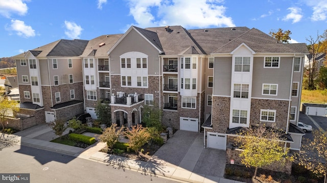 view of building exterior with a residential view, an attached garage, and driveway