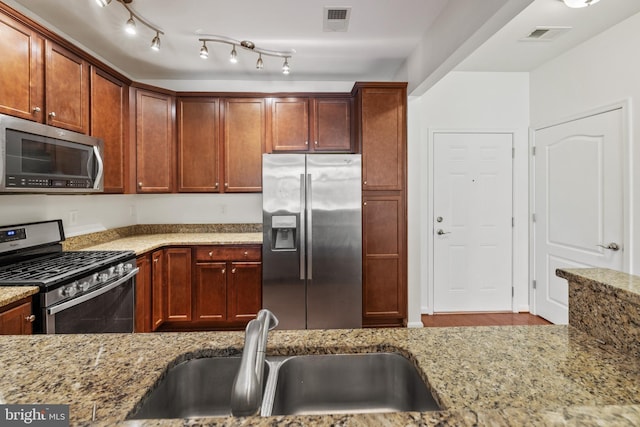 kitchen with a sink, visible vents, light stone counters, and appliances with stainless steel finishes