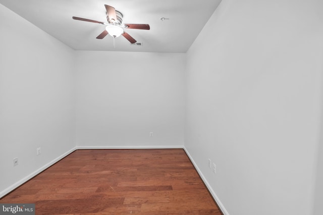 spare room featuring wood finished floors, a ceiling fan, baseboards, and visible vents