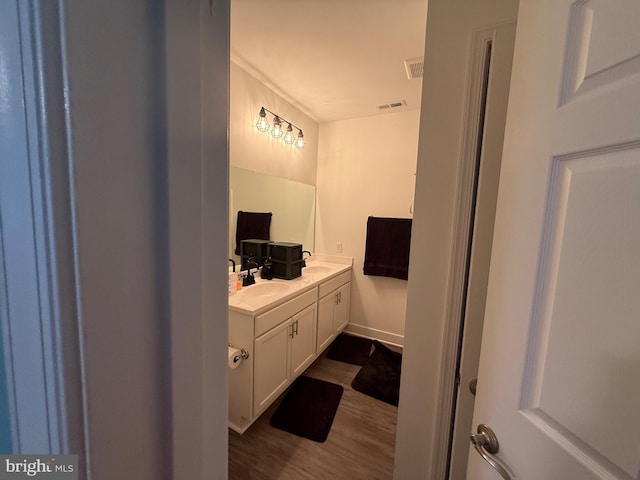 full bath with double vanity, visible vents, a sink, and wood finished floors