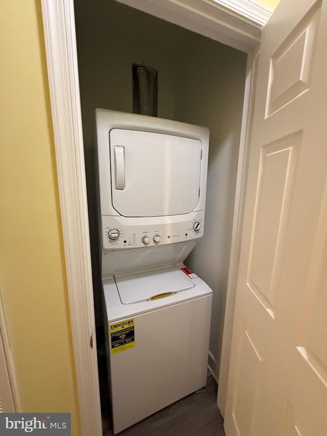 clothes washing area featuring laundry area, stacked washer / dryer, and dark wood finished floors