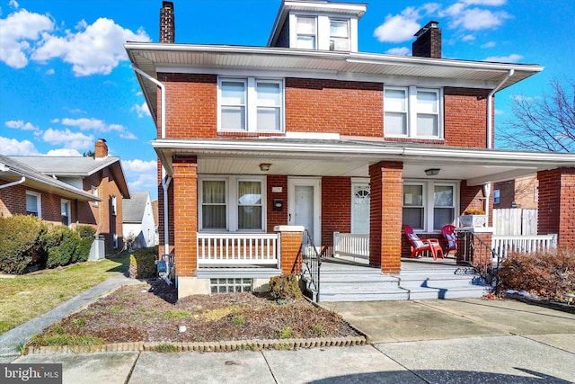 traditional style home featuring covered porch, brick siding, a chimney, and central AC unit