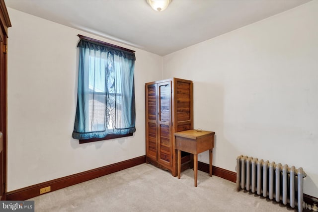 bedroom featuring light carpet, radiator heating unit, and baseboards