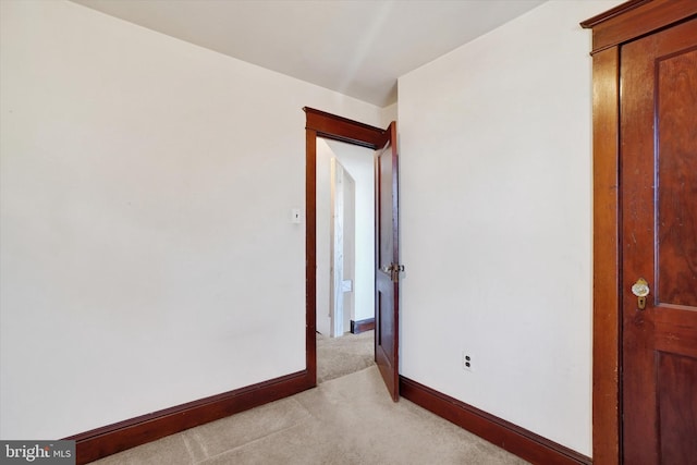 unfurnished room featuring light colored carpet and baseboards