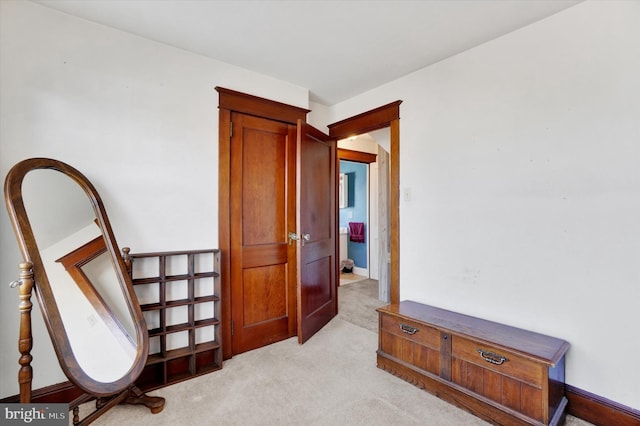 living area featuring baseboards and light colored carpet