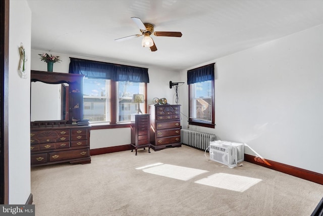 carpeted bedroom with ceiling fan, radiator heating unit, a wall unit AC, and baseboards