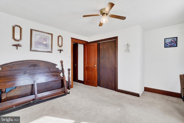 bedroom with light carpet, ceiling fan, a closet, and baseboards