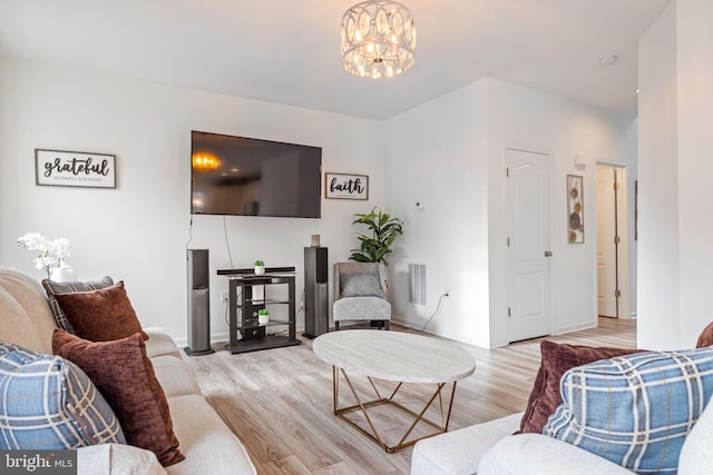 living room with visible vents, a notable chandelier, and wood finished floors