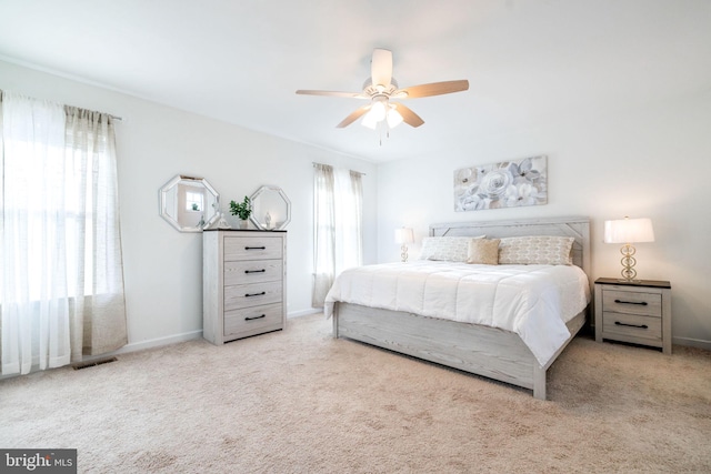 carpeted bedroom featuring a ceiling fan, visible vents, and baseboards