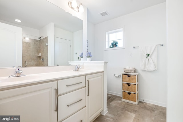 full bath featuring double vanity, visible vents, a tile shower, and a sink