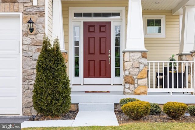 entrance to property featuring a garage and stone siding