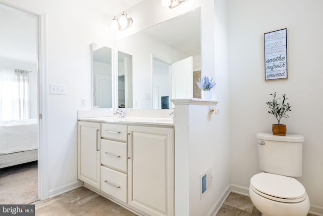 ensuite bathroom with double vanity, baseboards, toilet, and ensuite bathroom