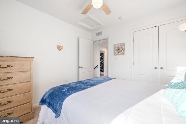 carpeted bedroom with ceiling fan, a closet, visible vents, and attic access