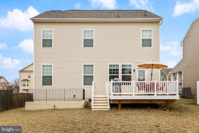 back of property with a wooden deck, fence, and a yard