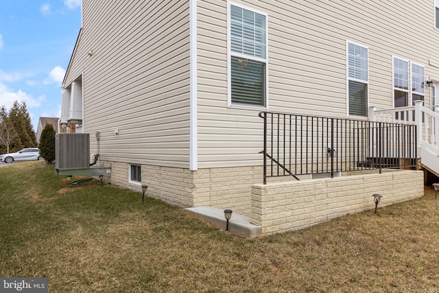 view of side of home with central AC and a lawn