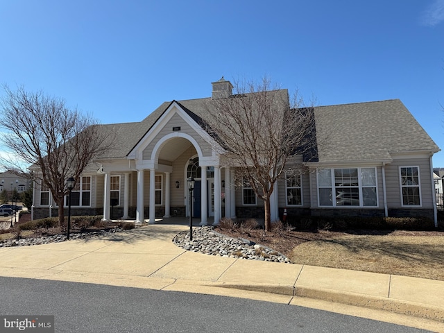 view of front of house with driveway, a shingled roof, and a chimney