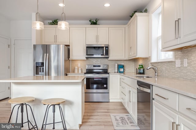 kitchen featuring a kitchen bar, decorative backsplash, stainless steel appliances, and a sink