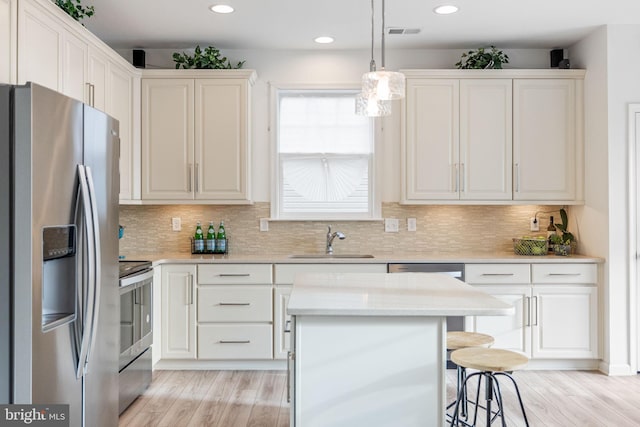 kitchen featuring a kitchen bar, decorative backsplash, stainless steel appliances, and a sink