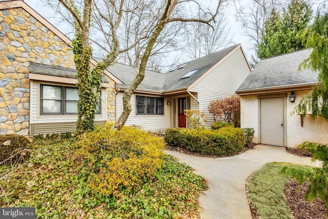 view of front of house with stone siding and a shingled roof