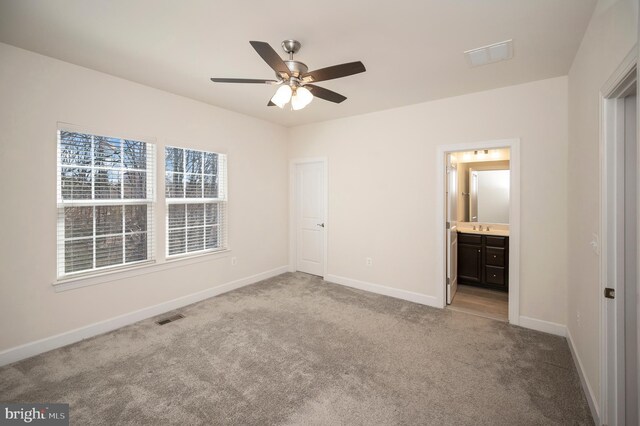 unfurnished bedroom featuring carpet floors, a sink, visible vents, baseboards, and ensuite bath