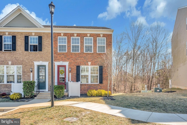 multi unit property featuring a front lawn and brick siding