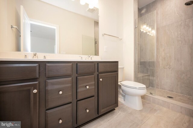 full bath featuring a tile shower, double vanity, a sink, and toilet