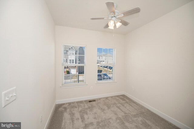 spare room featuring carpet, visible vents, baseboards, and a ceiling fan