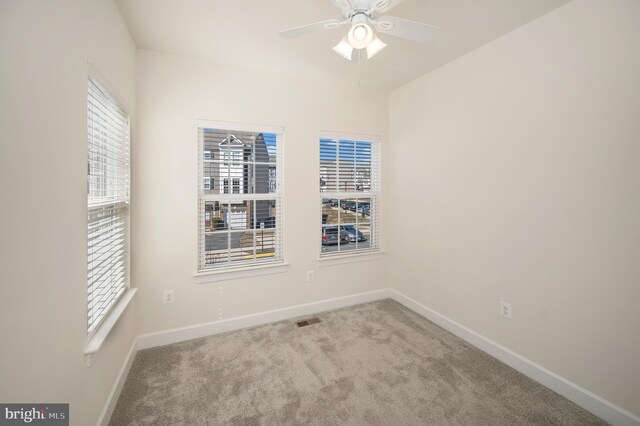 carpeted spare room with a ceiling fan, visible vents, and baseboards