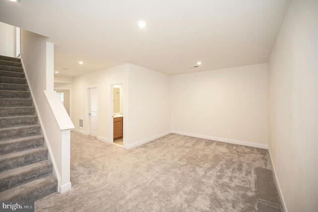 unfurnished room with recessed lighting, light carpet, baseboards, and stairs