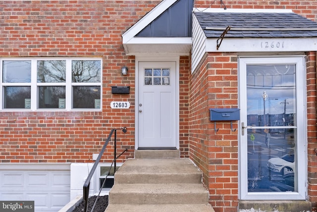 property entrance with a shingled roof and brick siding