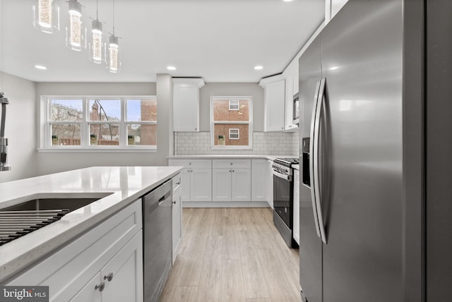 kitchen featuring stainless steel appliances, pendant lighting, white cabinets, and decorative backsplash