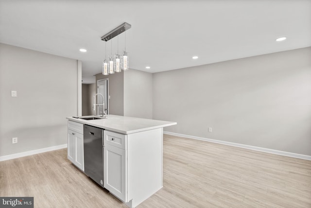 kitchen featuring a center island with sink, light countertops, stainless steel dishwasher, white cabinets, and a sink