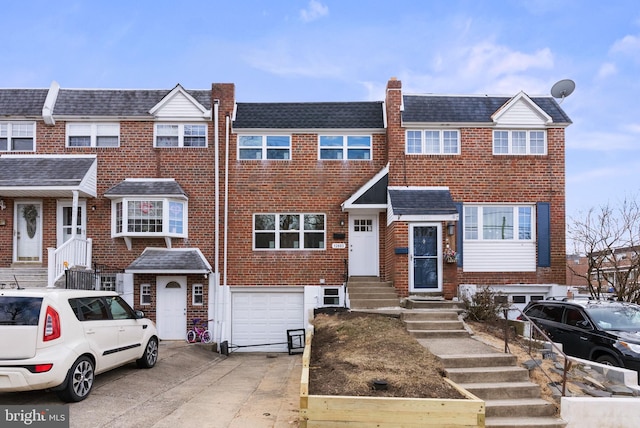 multi unit property featuring an attached garage, concrete driveway, and brick siding