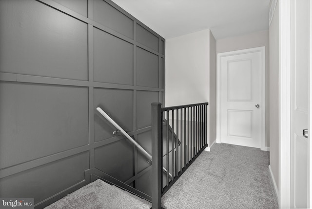 staircase featuring baseboards, carpet floors, and a decorative wall