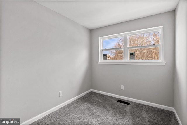 spare room featuring carpet floors, visible vents, and baseboards