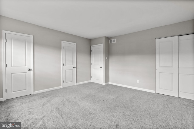 unfurnished bedroom featuring a closet, carpet, visible vents, and baseboards