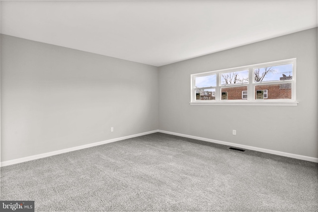 carpeted spare room featuring baseboards and visible vents