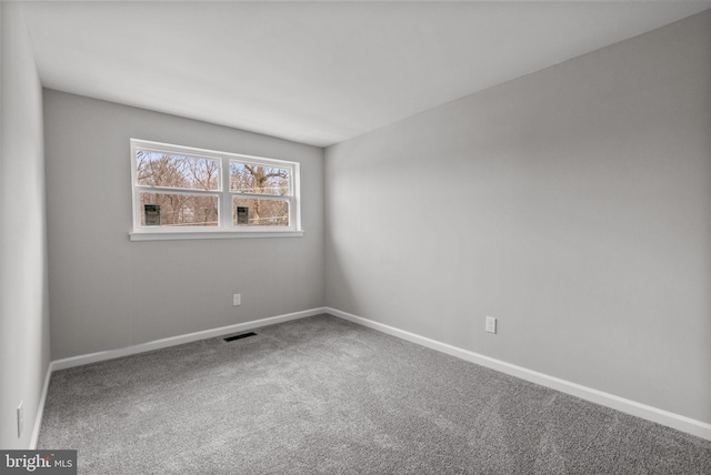 carpeted spare room with visible vents and baseboards