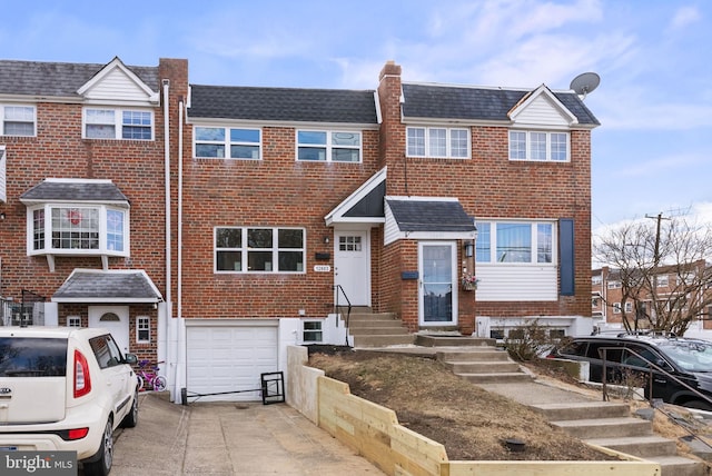 multi unit property featuring concrete driveway, brick siding, and an attached garage